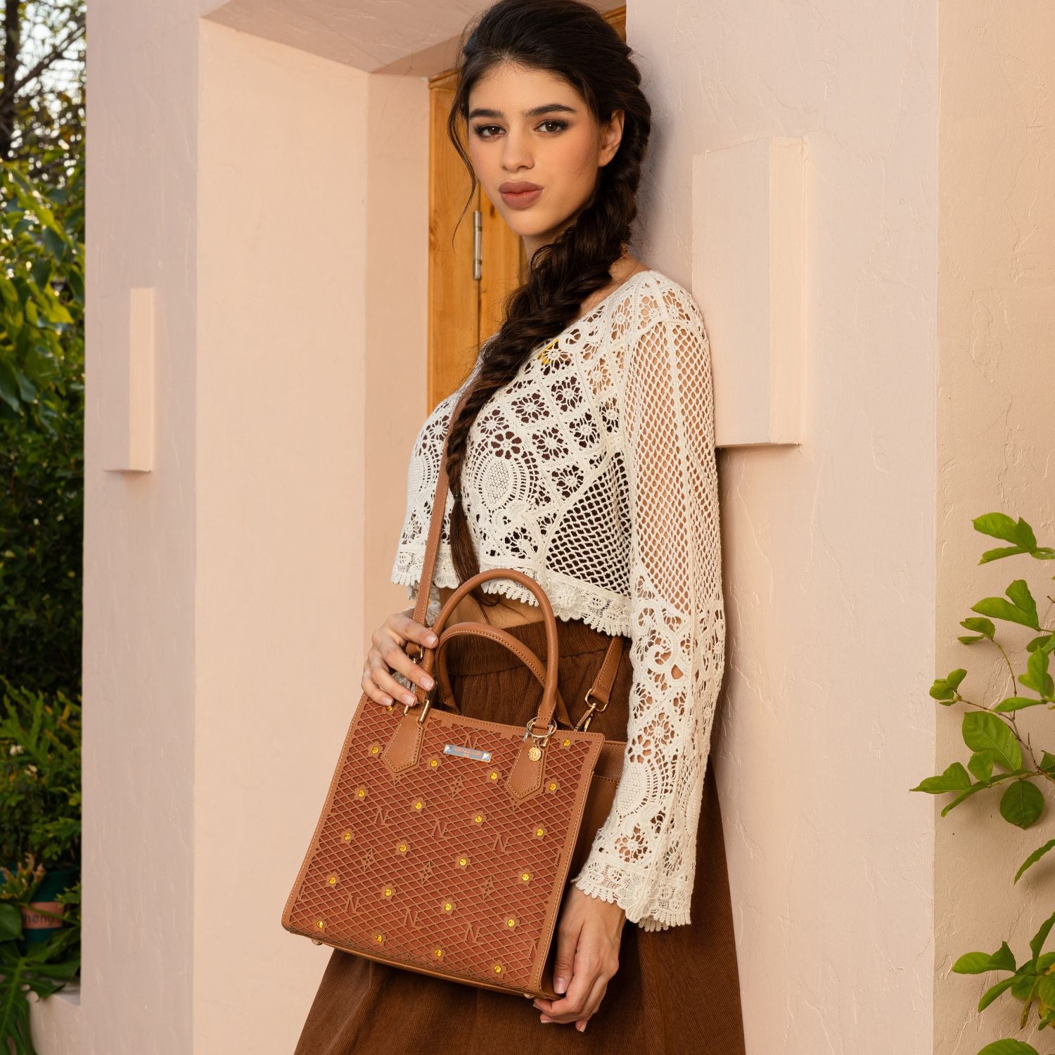 WOMEN  IN A IVORY CROCKET CROP TOP AND BROWN SKIRT, CARRYING OUR BROWN GRACIE STRUCTURED TOTE  SET IN A MODERN BACKGROUND. 