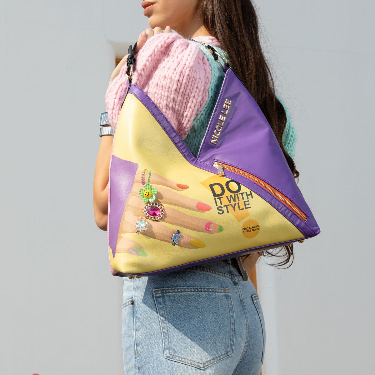 WOMEN IN A MULTI COLOR TOP AND BLUE JEANS CARRING ON HER SHOULDER OUR NICOLE LEE NAIL POLISH HOBO BAG