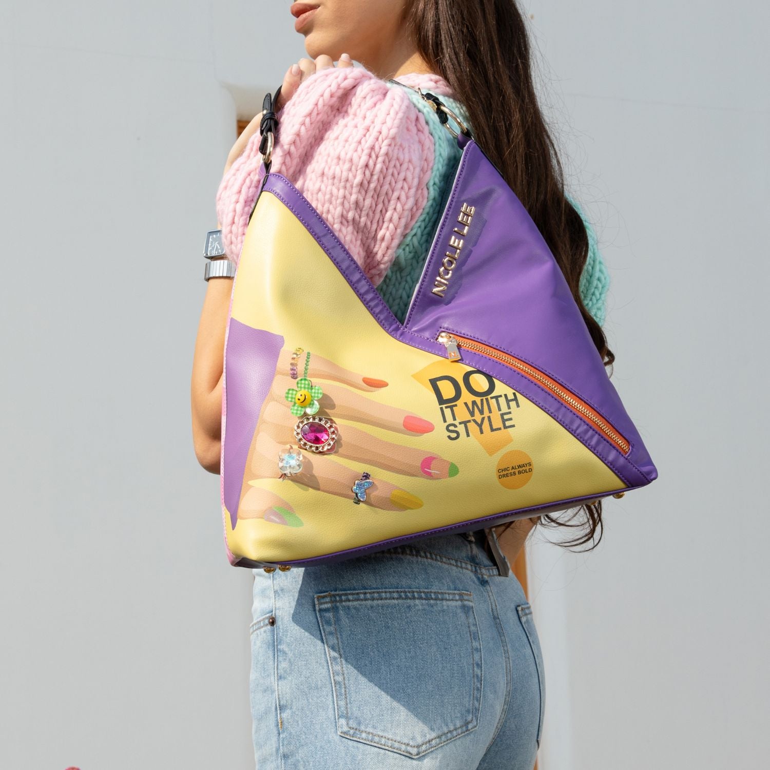 WOMEN IN A MULTI COLOR TOP AND BLUE JEANS CARRING ON HER SHOULDER OUR NICOLE LEE NAIL POLISH HOBO BAG