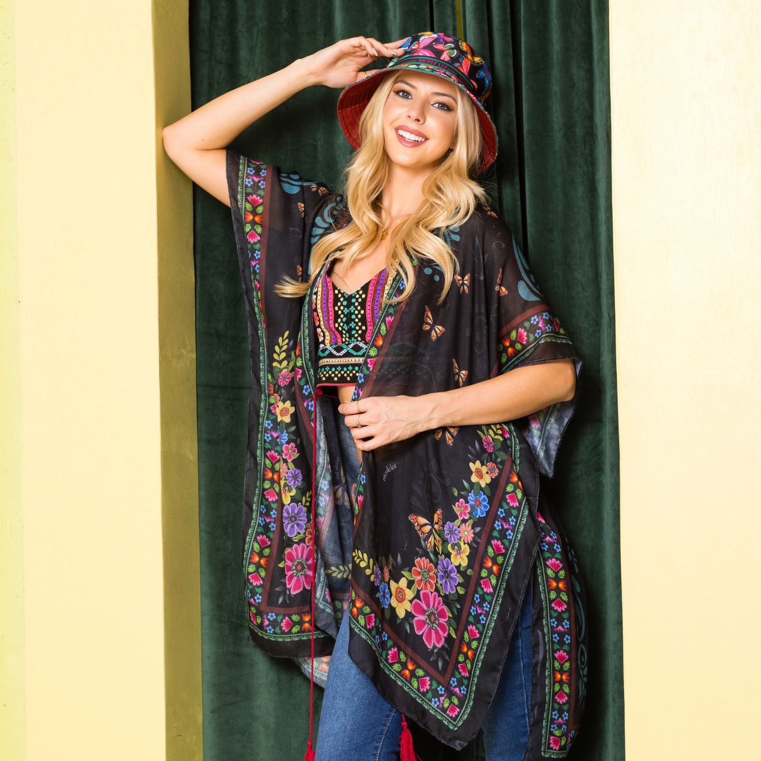 Woman in a colorful crop top and blue jeans stylishly posing and showing off her Kimono Nicole Lee in Alma de Colores design.