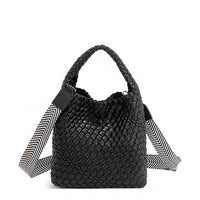 Introducing Juni from Nodu Nadu by Nicole Lee, a versatile and slouchy chic handbag with a removable pouch inside. Crafted in braided vegan leather with an optional, adjustable chevron striped shoulder strap for varied carrying options so you can wear it across the body or by the top handle for a sleek look. Pictured in a classic, timeless black shade with a tonal black and white striped shoulder strap.