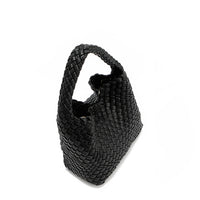 Top angle of Juni handbag crafted in braided vegan leather in classic, timeless black with a top handle (5" drop) and open slip compartment secured with a magnetic snap closure. Slouchy, relaxed silhouette offers a chic and laid-back yet refined look.