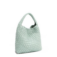 Back angle of Juni handbag crafted in braided vegan leather in pastel, dusty blue with a top handle (5" drop) and open slip compartment secured with a magnetic snap closure. Slouchy, relaxed silhouette offers a chic and laid-back yet refined look.