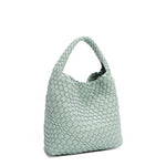 Front angle of Juni handbag crafted in braided vegan leather in pastel, dusty blue with a top handle (5" drop) and open slip compartment secured with a magnetic snap closure. Slouchy, relaxed silhouette offers a chic and laid-back yet refined look.