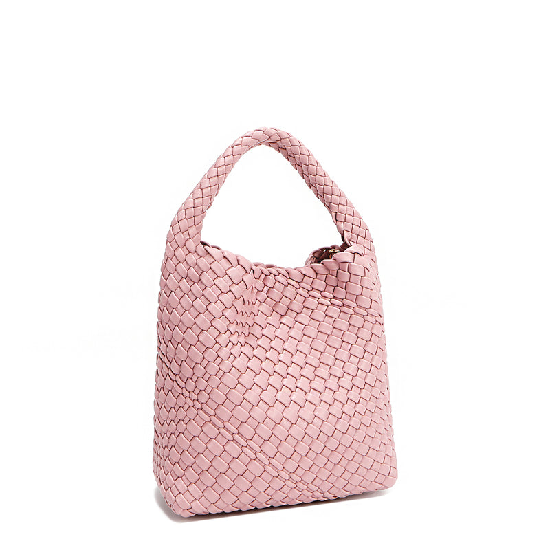 Front angle of Juni handbag crafted in braided vegan leather in pastel, dusty pink with a top handle (5" drop) and open slip compartment secured with a magnetic snap closure. Slouchy, relaxed silhouette offers a chic and laid-back yet refined look.