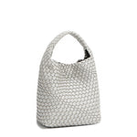 Back angle of Juni handbag crafted in braided vegan leather in metallic silver with a top handle (5" drop) and open slip compartment secured with a magnetic snap closure. Slouchy, relaxed silhouette offers a chic and laid-back yet refined look.