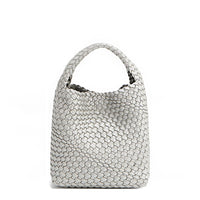 Juni handbag crafted in braided vegan leather in metallic silver with a top handle (5" drop) and open slip compartment secured with a magnetic snap closure. Slouchy, relaxed silhouette offers a chic and laid-back yet refined look.