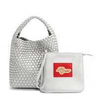 Soft, slouchy, and effortlessly chic—meet Juni from Nodu Nadu by Nicole Lee. Crafted from braided vegan leather, this beauty boasts a relaxed silhouette, a bonus zip pouch inside, and an optional matching strap. The ultimate go-anywhere, carry-everything statement piece—style it your way, every day! Available in a metallic silver shade along with even more versatile and on-trend tones to express your unique style. Each Juni bag comes with its own removable zip pouch in a solid matching color.