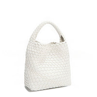 Front angle of Juni handbag crafted in braided vegan leather in classic, timeless white with a top handle (5" drop) and open slip compartment secured with a magnetic snap closure. Slouchy, relaxed silhouette offers a chic and laid-back yet refined look.