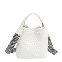 Introducing Juni from Nodu Nadu by Nicole Lee, a versatile and slouchy chic handbag with a removable pouch inside. Crafted in braided vegan leather with an optional, adjustable chevron striped shoulder strap for varied carrying options so you can wear it across the body or by the top handle for a sleek look. Pictured in a classic, timeless white shade with a black and white tonal striped shoulder strap.