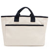 Back angle of the Emery handbag by Nodu Nadu in classic canvas-beige with navy blue trim. Made of polyester with dual top handles and a convenient black slip pocket to keep most-used items like your phone, keys, and planner close at hand. Dual top handles with a 3" drop allow you to carry this handbag by the top handles. 