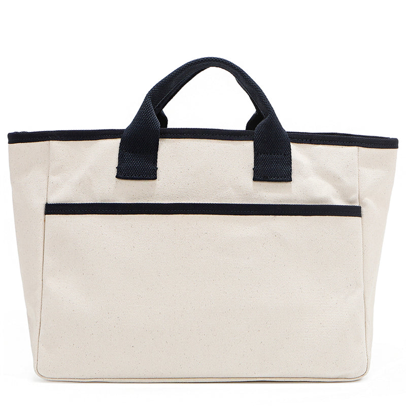 Back angle of the Emery handbag by Nodu Nadu in classic canvas-beige with navy blue trim. Made of polyester with dual top handles and a convenient black slip pocket to keep most-used items like your phone, keys, and planner close at hand. Dual top handles with a 3" drop allow you to carry this handbag by the top handles. 