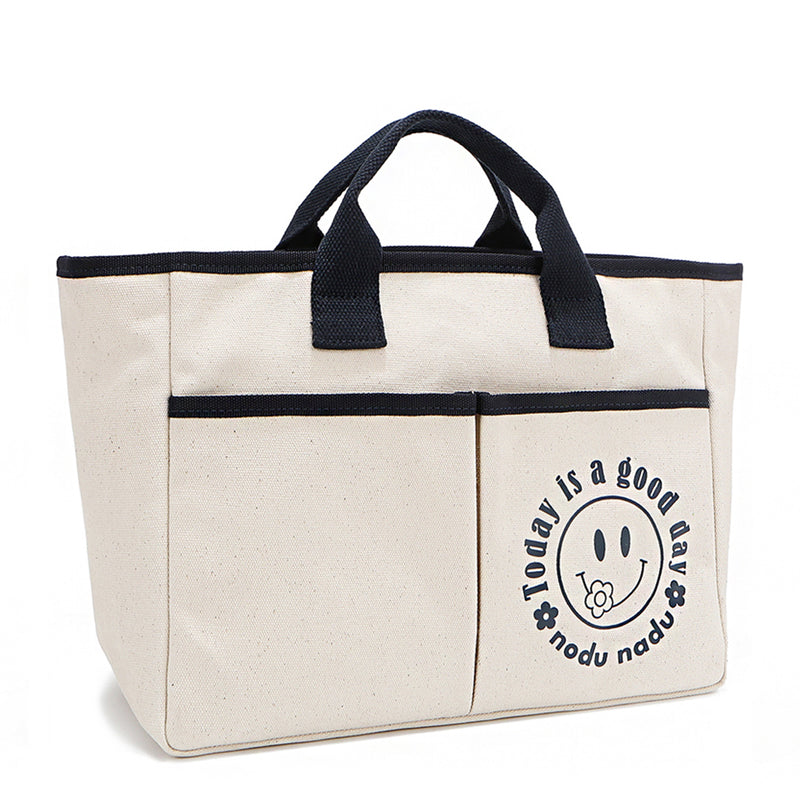 Your daily dose of positivity—now in bag form! With sleek trim details and a feel-good message, this everyday tote is here to remind you that yes, today (and every day) is a good one. Designed for both style and function, it features plenty of compartments inside like 2 front slip pockets. Pictured in classic, canvas-colored beige front angle view for a timeless statement that compliments any look from day to night! 