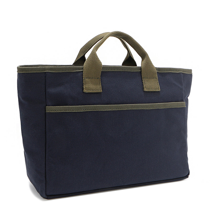 Back angle of the Emery Nodu Nadu tote bag in classic navy blue with moss green trim and dual straps. An open slip compartment in the back allows you to store items like your keys, journal, and more for convenient access. Rectangular silhouette for a classic, timeless feel. 