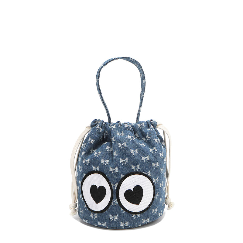 A blue bucket bag with a sweetheart bow print and heart-eye patches, featuring a top handle and a side drawstring closure.