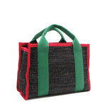 Back angle view of the Nodu Nadu small canvas Marley tote Bag in black. Accented with forest green straps and a bold red trim, this canvas features a subtle metallic shimmer that hits the light whenever you walk for a head-turning detail. 