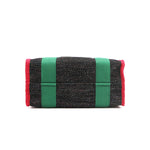 Structured, rectangular base of the Nodu Nadu Marley Bag in Black with grass green strap accents and bold red trim. 