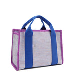 Back angle view of the Nodu Nadu small canvas Marley tote Bag in lavender. Accented with bold electric blue straps and a gorgeous purple trim, this canvas features a subtle metallic shimmer that hits the light whenever you walk for a head-turning detail. 