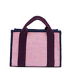 Back view of the Nodu Nadu small canvas Marley tote Bag in pink. Accented with eggplant purple straps and a navy blue trim, this canvas features a subtle metallic shimmer that hits the light whenever you walk for a head-turning detail. 