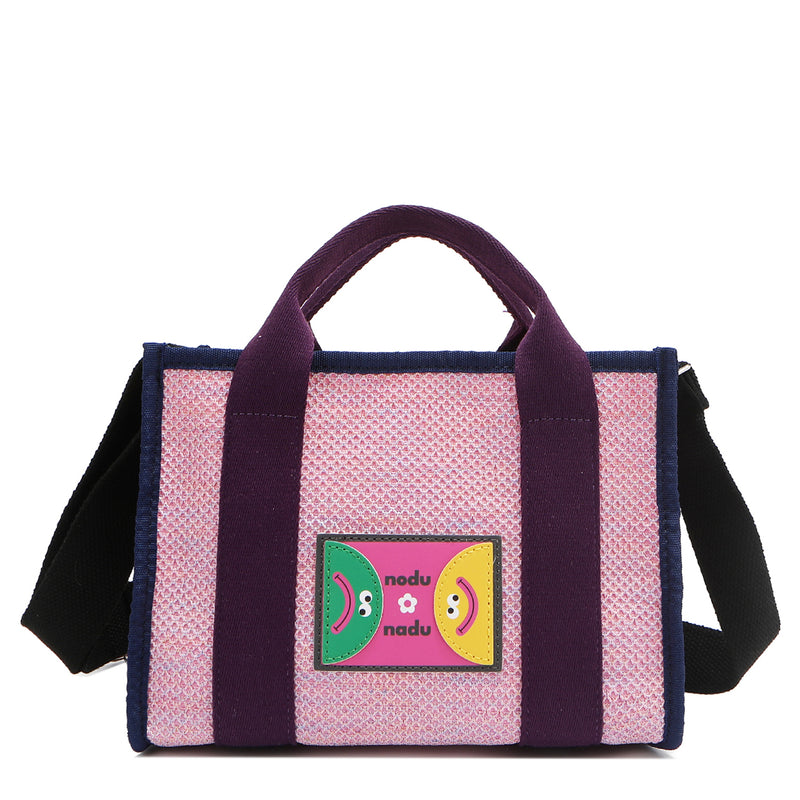 Front view of Nodu Nadu Marley Bag in Pink with optional, adjustable and detachable black wide shoulder strap attached to show varied carrying options. Wear this rectangular tote by the top handles or around the shoulder or across the body!