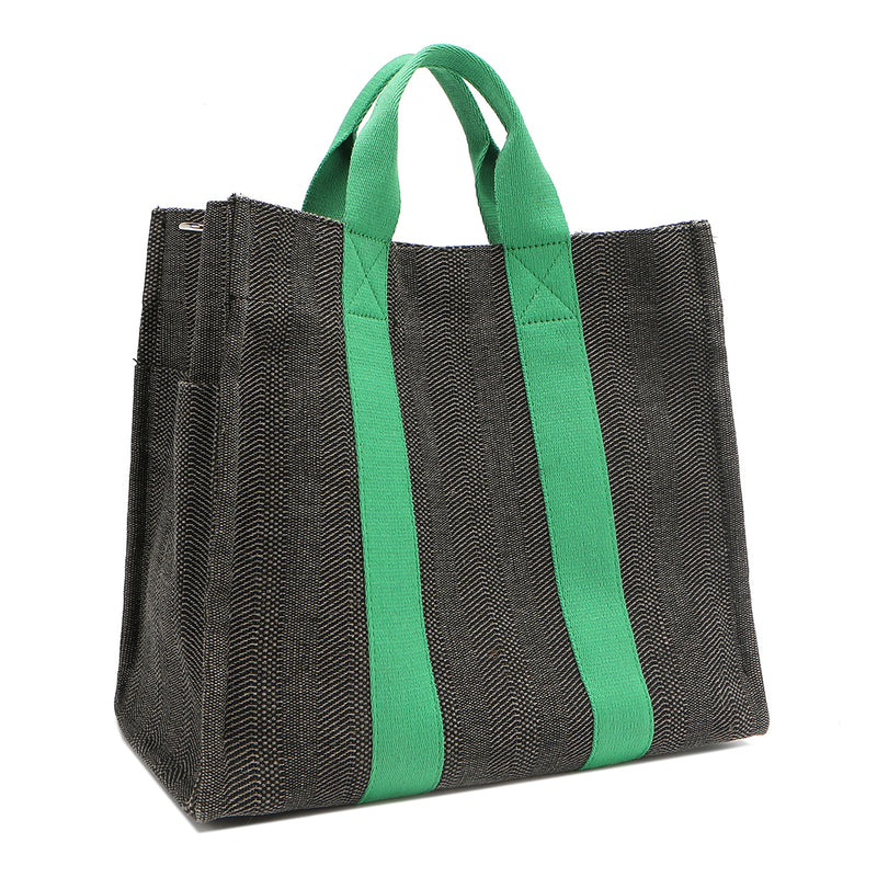 Back angle view of the Nodu Nadu Sawyer Bag in Black with grass green accents. Rectangular side view of the canvas bag shows the side slip pocket that can store any essentials you want close at hand. 