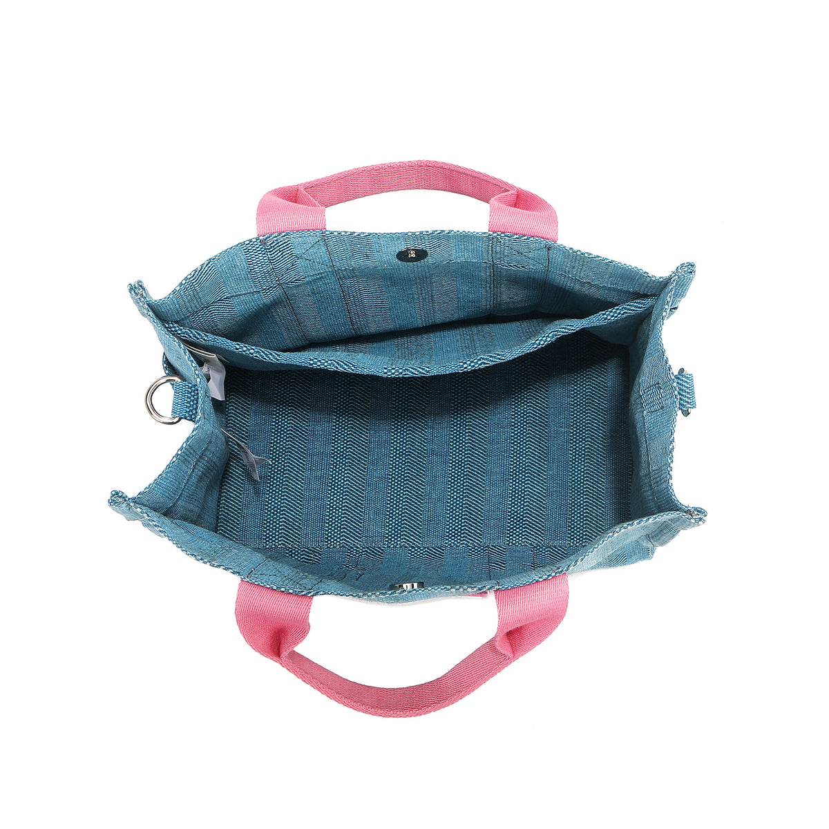 Nodu Nadu Sawyer Bag in Blue made of canvas with baby pink strap accents roomy interior opens up from its magnetic snap button closure to reveal an interior back slip compartment. Side D-rings for optional shoulder strap attachment provide varied carrying options. 