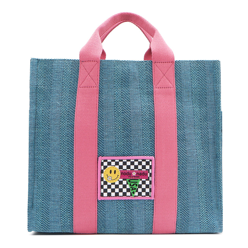 Your must-have carryall for school, weekends, and everything in between! Designed with a soft, relaxed silhouette, the Nodu Nadu Sawyer in Blue offers plenty of space to keep notebooks and loose essentials effortlessly organized—so you're always ready to grab and go! Light blue canvas paired with baby pink strap accents. 