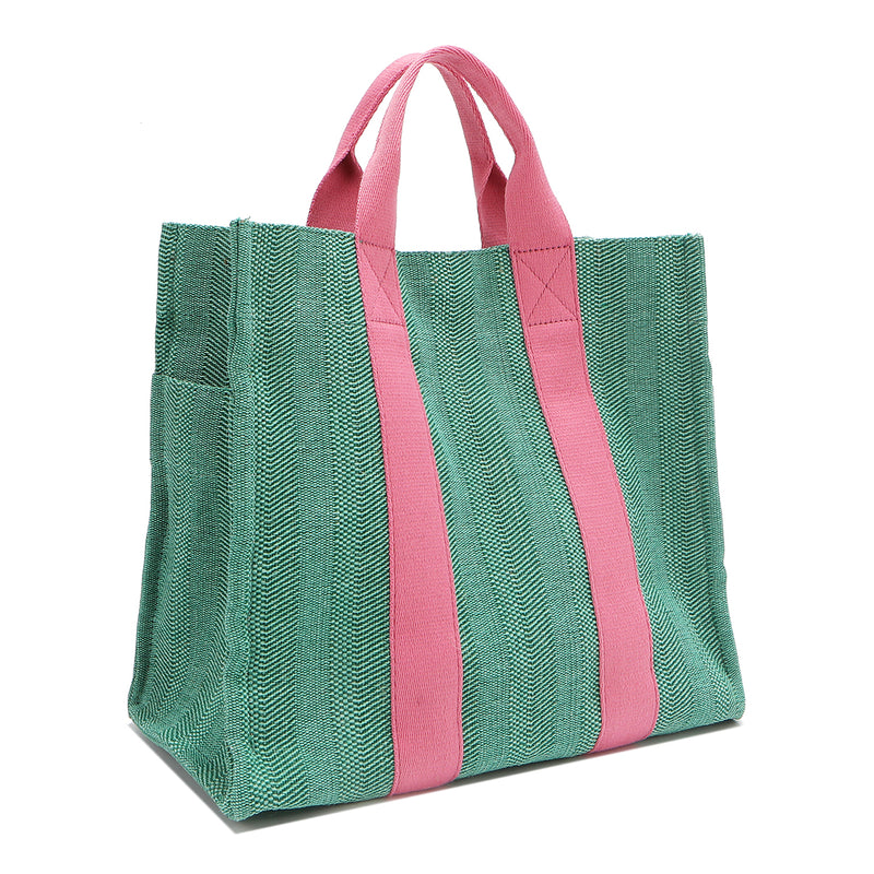 Back angle view of the Nodu Nadu Sawyer Bag in Green with baby pink accents. Rectangular side view of the canvas bag shows the side slip pocket that can store any essentials you want close at hand. 