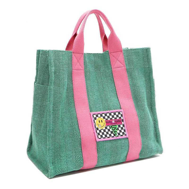 Front angle view of the Nodu Nadu Sawyer Bag in Green. Crafted in durable canvas with side D-rings for optional shoulder strap attachment so you can wear this bag as a handbag, shoulder bag, or crossbody! It also features side slip pockets for a convenient touch. 