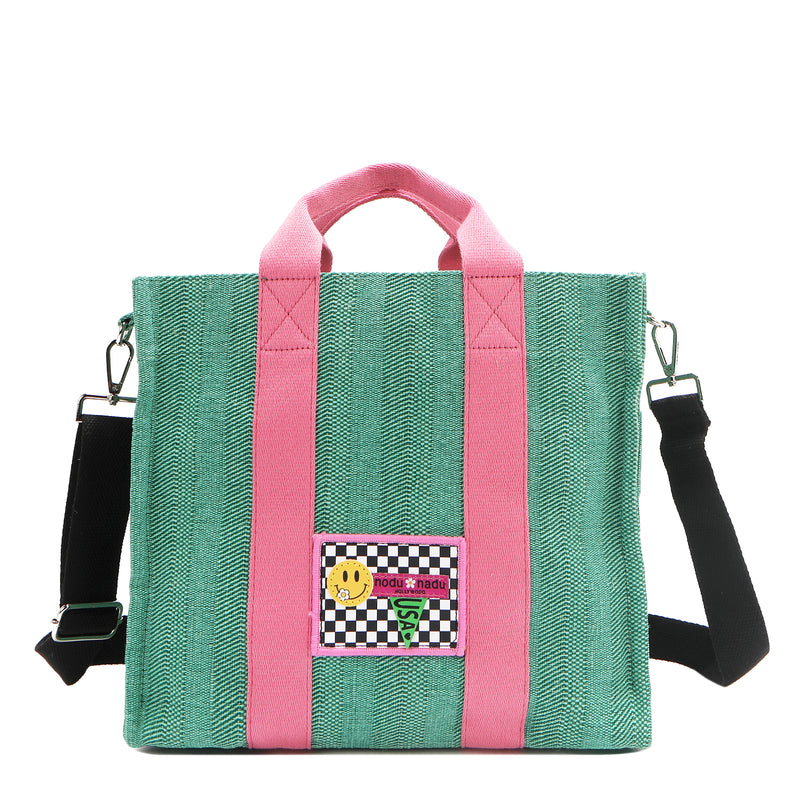 Nodu Nadu Sawyer Bag in Green with baby pink strap accents and paired with an adjustable, optional black wide shoulder strap. Wear this bag by the top handles or across the body thanks to the versatile shoulder strap options. 