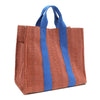 Back angle view of the Nodu Nadu Sawyer Bag in Orange/Sienna brown with bold blue accents. Rectangular side view of the canvas bag shows the side slip pocket that can store any essentials you want close at hand. 