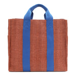 Back of the Nodu Nadu Sawyer Bag in Orange. Orange/sienna brown-colored canvas accented with bold electric blue straps for a pop of trendy color and vibrance. Rectangular silhouette provides a sense of classic timelessness so you can dress up or dress down this everyday style. 