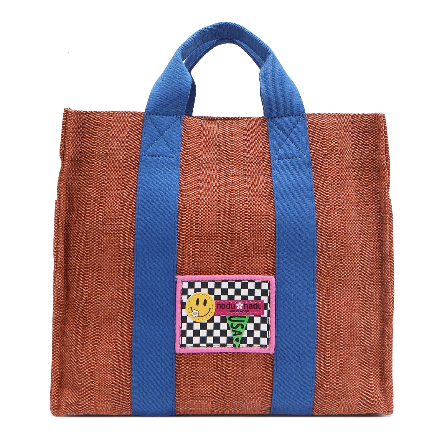 Your must-have carryall for school, weekends, and everything in between! Designed with a soft, relaxed silhouette, the Nodu Nadu Sawyer in Orange offers plenty of space to keep notebooks and loose essentials effortlessly organized—so you're always ready to grab and go! Burnt orange/sienna brown-colored canvas paired with bold blue strap accents. 