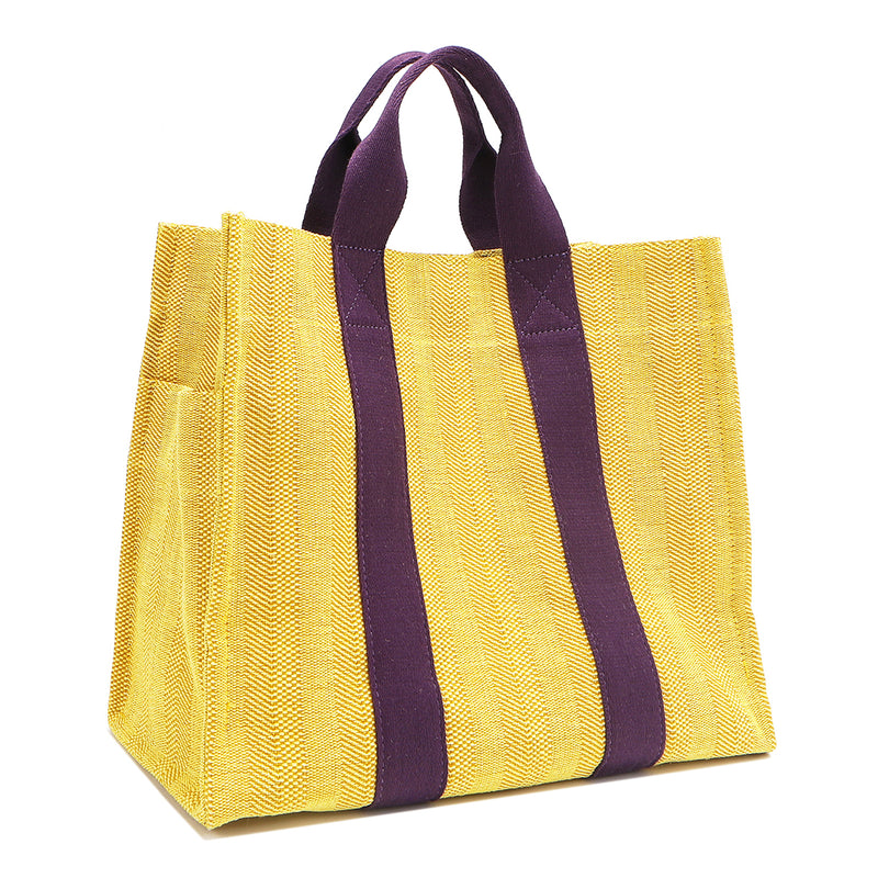 Back angle view of the Nodu Nadu Sawyer Bag in Yellow with eggplant purple accents. Rectangular side view of the canvas bag shows the side slip pocket that can store any essentials you want close at hand. 