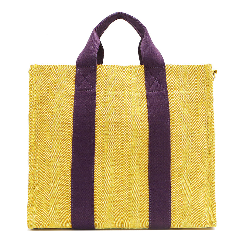 Back view of the Nodu Nadu Sawyer Bag in Yellow with eggplant purple strap accents. Durable, canvas material in a rectangular silhouette offers endless expression to mix and match your style no matter the season or occasion. 