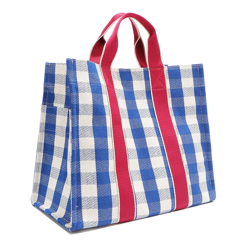 Back corner angle of the Nodu Nadu Canvas Bag in Blue – featuring wide blue and white gingham print and vertical pink webbing. Side view shows the deep open slip pockets that you can store most-used items like your phone, keys, and makeup, close at hand! 