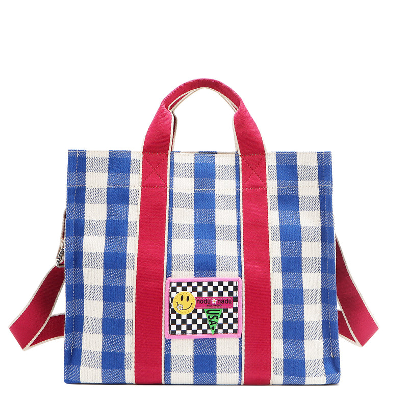 Your new go-to bag with a gingham twist! The Nodu Nadu Blair Bag in Blue brings a perfect mix of timeless charm and everyday durability, featuring a structured yet roomy silhouette, handy side pockets, and a back slip compartment to keep your essentials effortlessly organized. Pictured with the optional, adjustable shoulder strap attached for varied carrying options and versatility when wearing. 