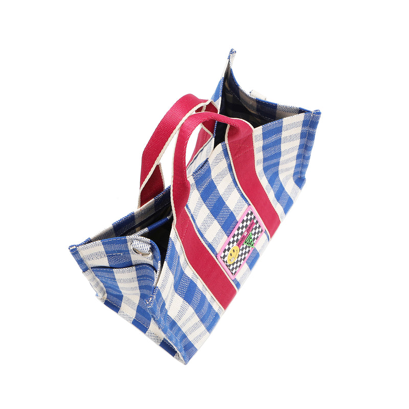 Top angle shot of the Nodu Nadu Blair bag in blue with blue and white gingham print and hot pink shoulder straps. The top view shows the bag closed with the magnetic snap button closures and shows the side features like the open slip side pockets and the D-ring for optional shoulder strap attachment. 