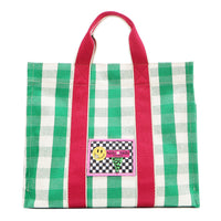 Front view of the Nodu Nadu Canvas Blair Bag in green with bold pink handles and a playful checkered patch in black and white  with the Nodu Nadu smiley face logo. Dual top handles with a 4.5" drop paired with a timeless, rectangular silhouette. 