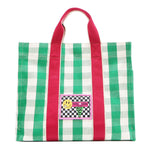 Front view of the Nodu Nadu Canvas Blair Bag in green with bold pink handles and a playful checkered patch in black and white  with the Nodu Nadu smiley face logo. Dual top handles with a 4.5" drop paired with a timeless, rectangular silhouette. 