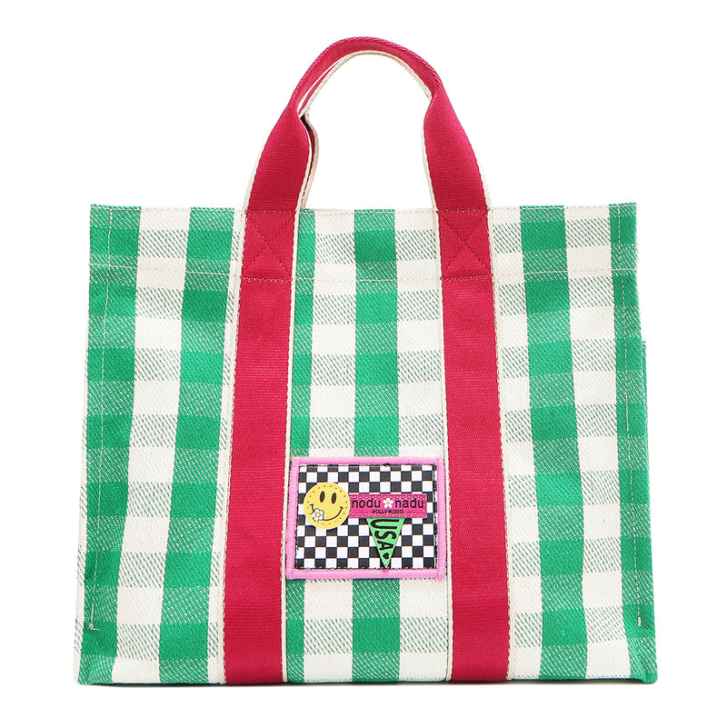 Front view of the Nodu Nadu Canvas Blair Bag in green with bold pink handles and a playful checkered patch in black and white  with the Nodu Nadu smiley face logo. Dual top handles with a 4.5" drop paired with a timeless, rectangular silhouette. 