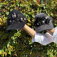 HOLDING OUR 2 CAPS IN OUR MIDNIGHT DESIGN SET IN A NATURE BACKROUND.