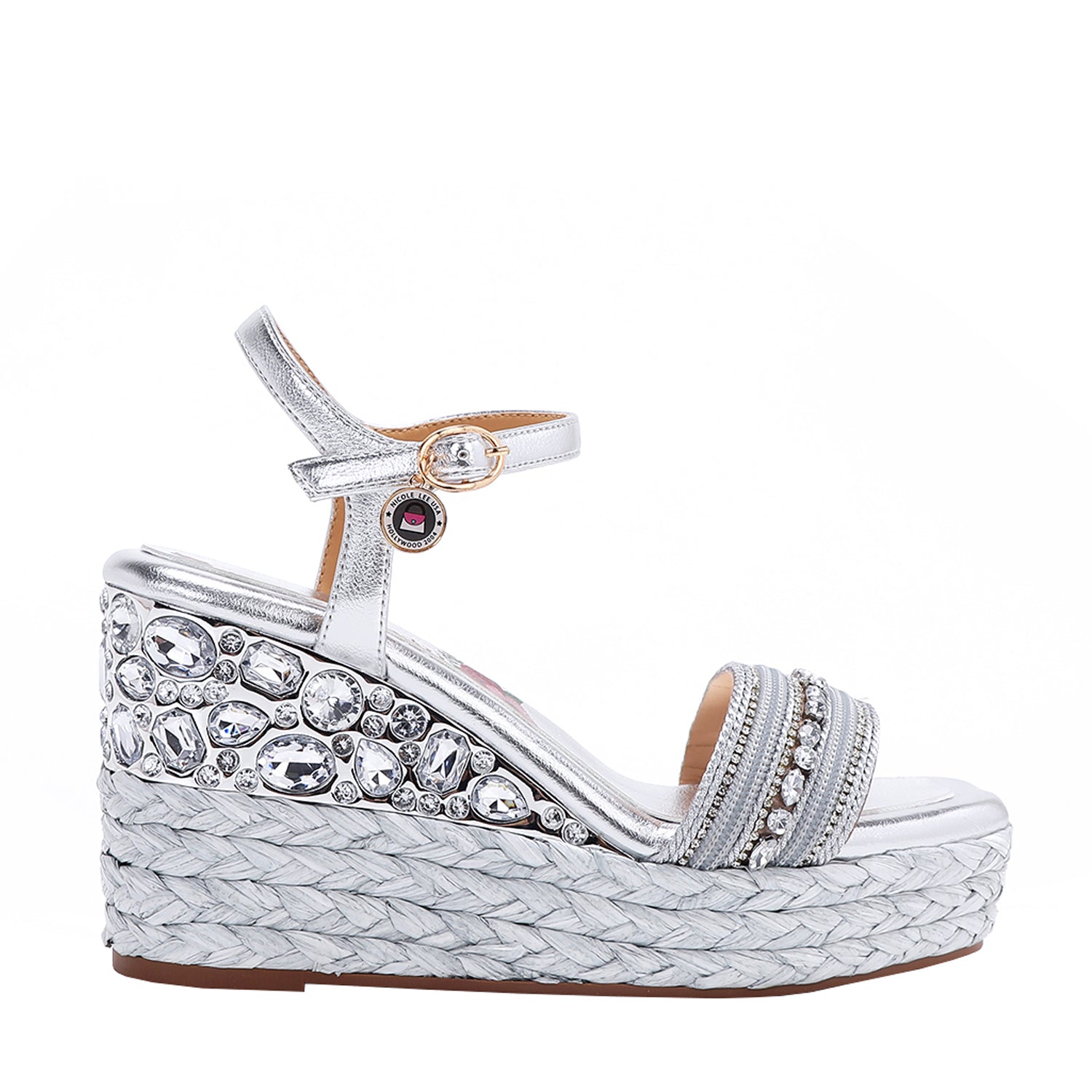 Kali Espadrille Wedge sandal in Silver.  Fitted with 1 adjustable buckle. The buckle has a small Nicole Lee Charm.The wedge is adorned with rhinestones and  braid detailing.