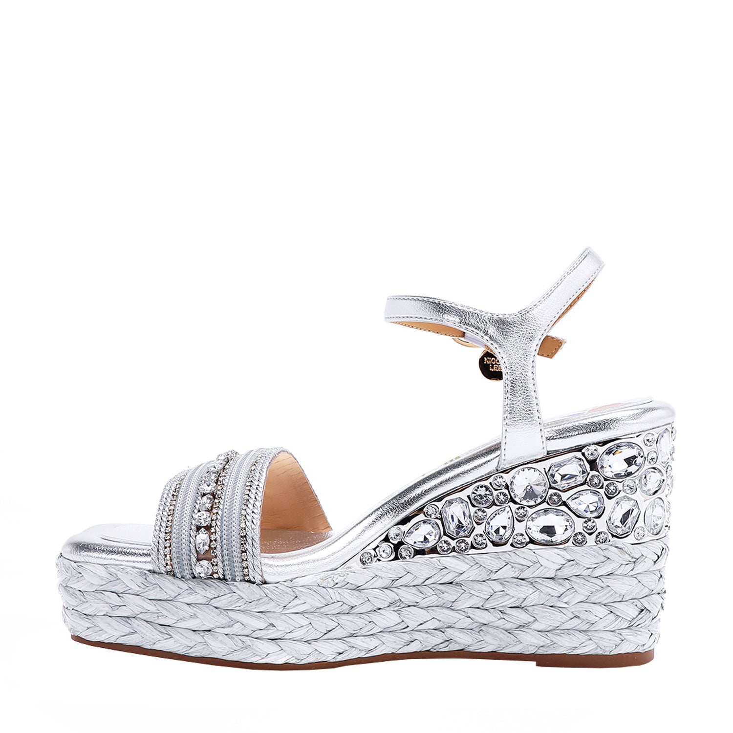 Kali Espadrille Wedge sandal in Silver.  Fitted with 1 adjustable buckle. The buckle has a small Nicole Lee Charm.The wedge is adorned with rhinestones and  braid detailing.